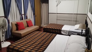 Habitación de hotel con dos camas, un sofá, un ventilador y un tendedero.