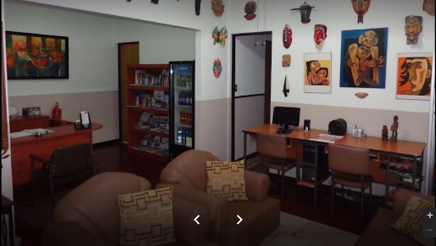 Una habitación con sofá, escritorio, estantería y varias decoraciones en la pared.