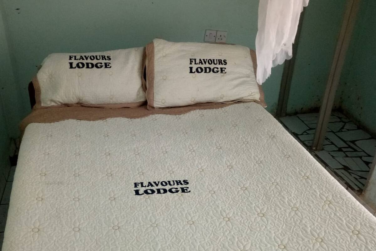 Una cama con colchón acolchado y almohadas con la etiqueta "FLAVOURS LODGE".