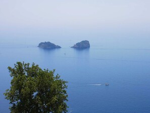 A calm sea with two small islands and a boat in the distance.