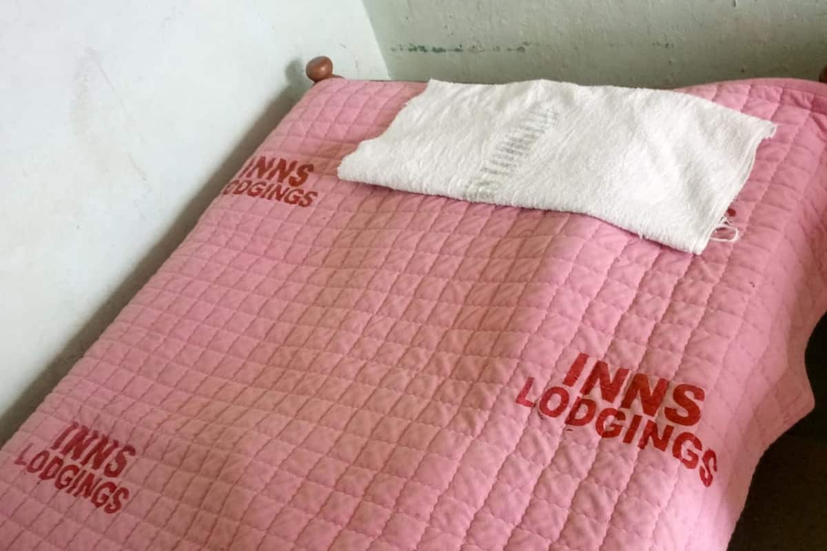 A pink quilted bedspread with the text "INNS LODGINGS" printed on it.