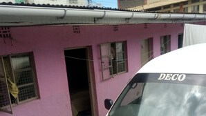 A white van parked in front of a pink building with a window and a door. - Inns Lodge (Naivasha)