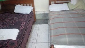 A small, simple room with two wooden beds, each with a pillow and a blanket. - Inns Lodge (Naivasha)