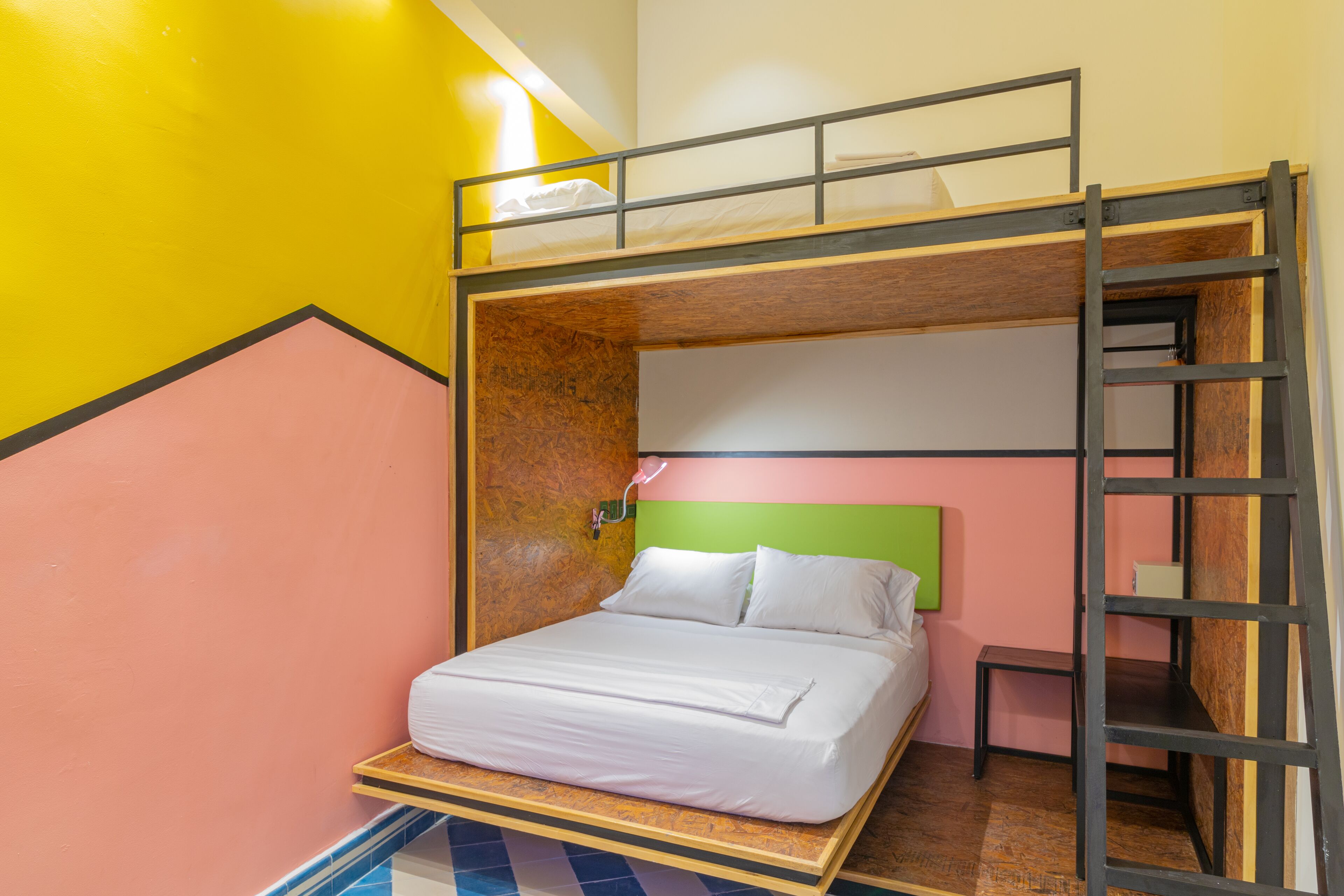 A bunk bed with a wooden ladder, a small bedside table, and a wall-mounted light fixture.