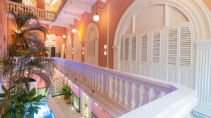 A multi-level hotel interior with a central atrium, a pool, and a balcony with a railing. - Casa Movida Hostel (Cartagena)