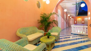 A corridor with wicker furniture, a potted plant, and a checkered floor. - Casa Movida Hostel (Cartagena)