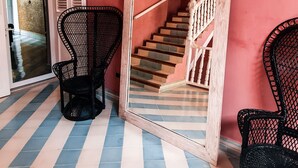 A room with a checkered floor, a staircase with white railings, and two black wicker chairs. - Casa Movida Hostel (Cartagena)