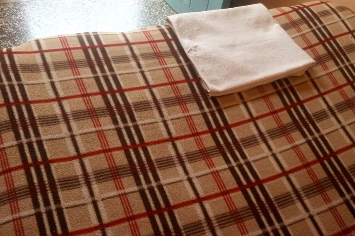 Un sofá estampado con diseño escocés y un cojín blanco.