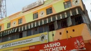 Een meerlaags gebouw met een Jasho Bar & Restaurant op de begane grond en een Jasho Beenhouwerij op de tweede verdieping.