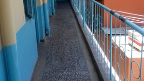 Een smalle gang met blauwe en oranje wanden, een metalen leuning aan één kant en een deur aan het einde.
