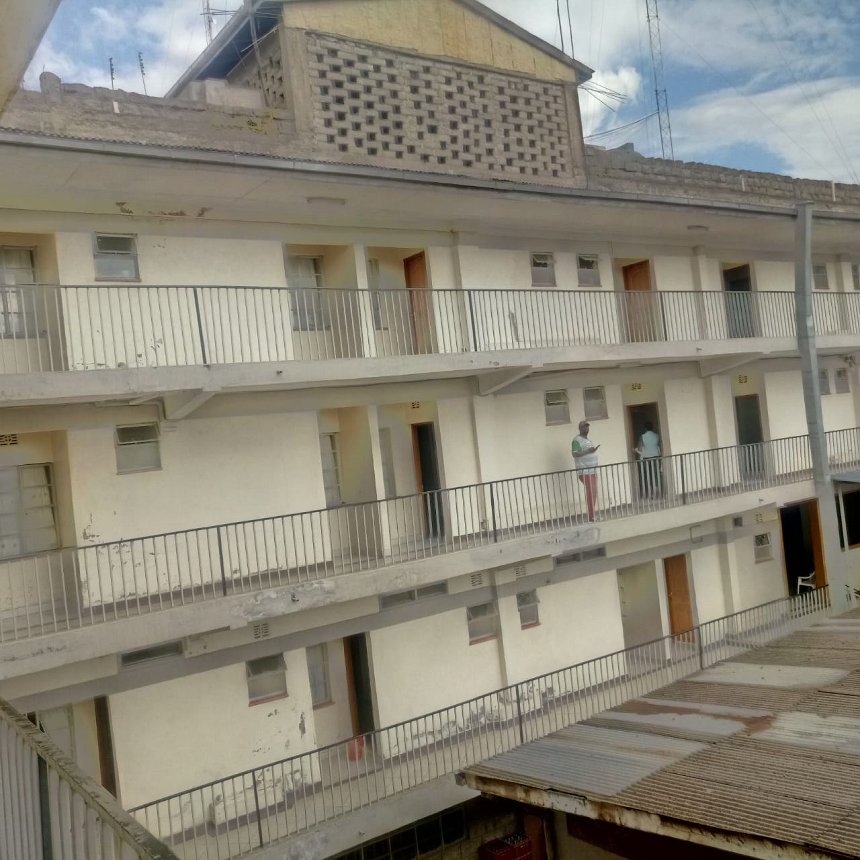 A multi-story building with balconies, a flat roof, and a visible power line.