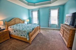 A bedroom with a wooden bed, a nightstand, a dresser, and a television. - Coastal Club * Luxury 5BR lake-front beach house (Lewes)