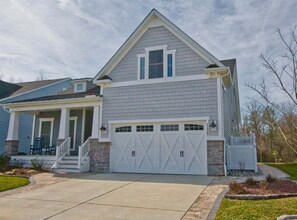 A two-story house with a front porch, a garage with double doors, and a small front yard. - Coastal Club * Luxury 5BR lake-front beach house (Lewes)