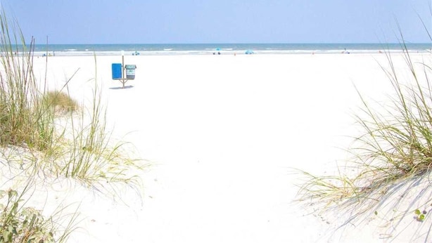 A beach with sand dunes and a blue sign in the distance. - Ocean Paradise, 3 Bedrooms, Ocean Front, Wifi, Sleeps 10 (St. Augustine)
