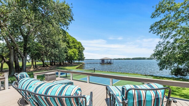 Una terraza con mobiliario exterior a rayas que da a un lago.