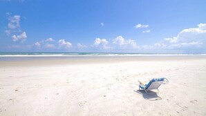 Una playa con una sola silla y un cielo despejado.
