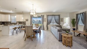 A spacious living area with a dining table, chairs, a sofa, and a kitchen in the background. - Perfect Family Getaway! Ultimate WATERPARK Resort Near Disney! (Davenport)