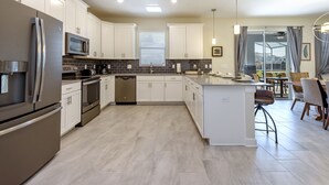 A modern kitchen with stainless steel appliances, white cabinetry, and a central island. - Perfect Family Getaway! Ultimate WATERPARK Resort Near Disney! (Davenport)