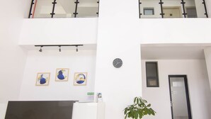 Un vestíbulo amplio con techo alto, una columna central y una planta en maceta.