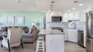 Una cocina moderna con armarios blancos, un refrigerador de acero inoxidable y una isla central.