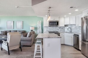 A modern kitchen with white cabinets, a stainless steel refrigerator, and a central island.