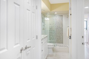 A modern bathroom with a glass shower enclosure, a toilet, and a sink.