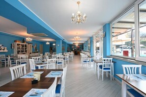 A spacious restaurant with high ceilings, chandeliers, and a view through large windows. - Hotel Paradiso Verde (Bibbona)