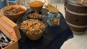 Comedor con mesas dispuestas para un bufé, que incluye cuencos de cereal y frutos secos, además de un barril.