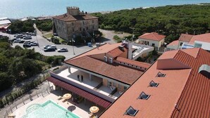 Un hotel costero con piscina, un edificio de estilo castillo y vista al mar.