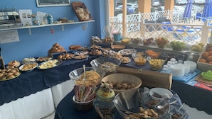 Una mesa de buffet con diferentes platos y una vista de coches aparcados afuera.
