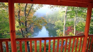 Une cabane en bois offrant une vue sur une zone boisée et un lac.