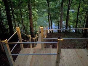 Una scala in legno con ringhiere in metallo che conduce in una zona boschiva.