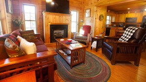 L’intérieur d’un chalet confortable, avec une cheminée, des meubles en bois et un téléviseur.