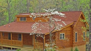 Une cabane en rondins dotée d’un balcon et d’une lucarne au deuxième étage.