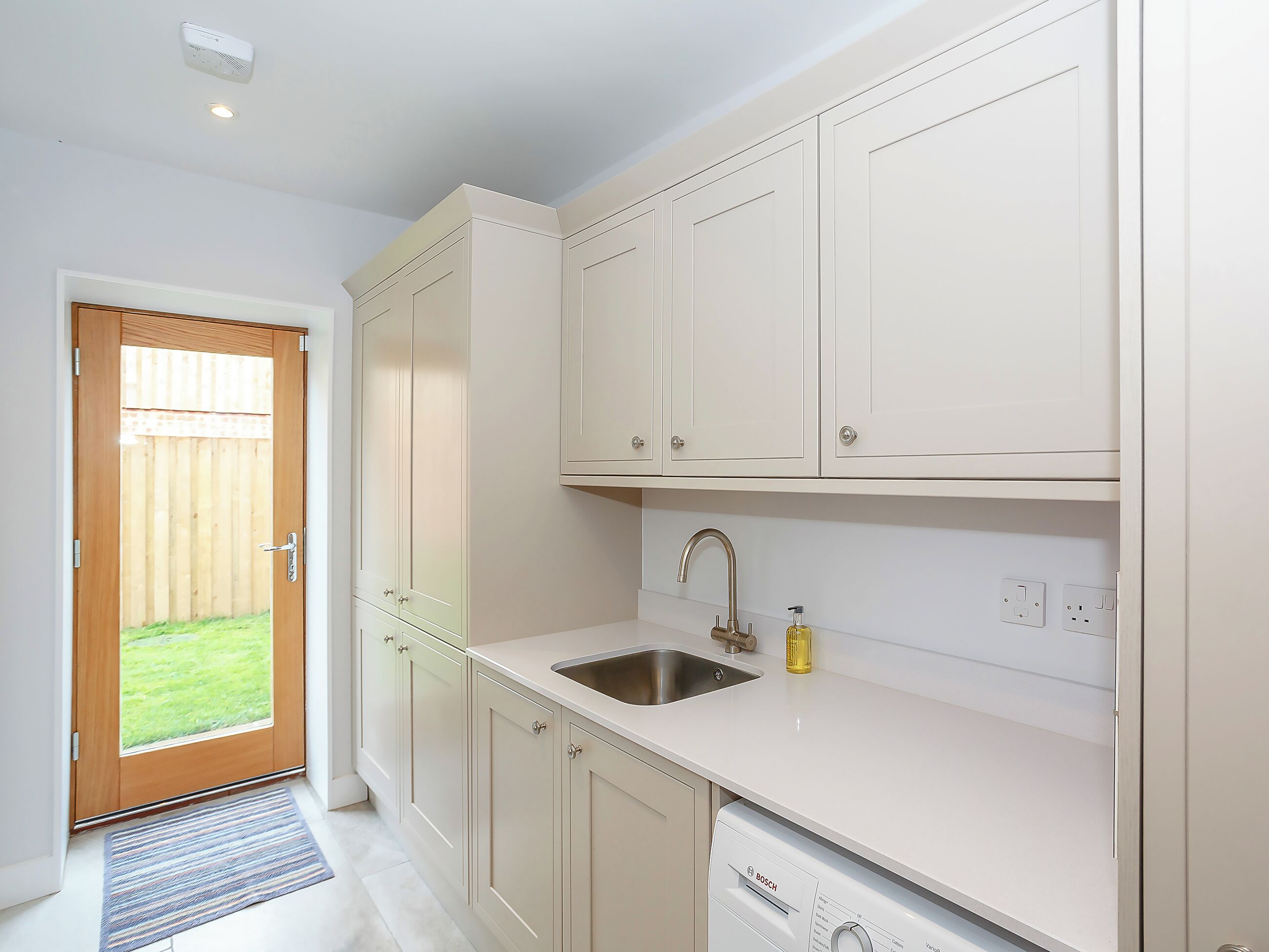 A kitchen with white cabinets, a stainless steel sink, and a Bosch dishwasher.