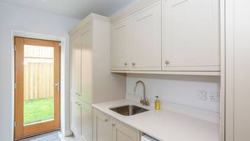 A kitchen with white cabinets, a stainless steel sink, and a Bosch dishwasher.