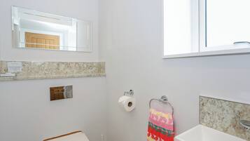 Une salle de bain équipée de toilettes, d’un lavabo, d’un miroir et d’un porte-serviettes.