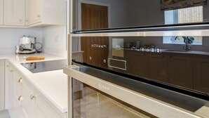 Una cocina moderna con electrodomésticos de acero inoxidable, armarios blancos y una puerta de madera.