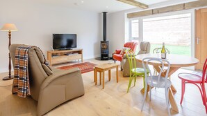 Una sala de estar con sofá, televisión, chimenea y un comedor con sillas y una mesa.