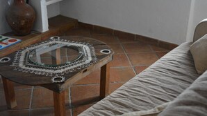 Une table en bois rustique, agrémentée d’un miroir décoratif et de dentelle, un tapis tissé et un sol carrelé.