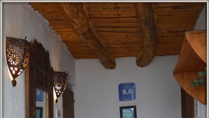 Un couloir étroit au sol carrelé, une petite table avec une chaise et un panneau indiquant le numéro de la chambre : 8.