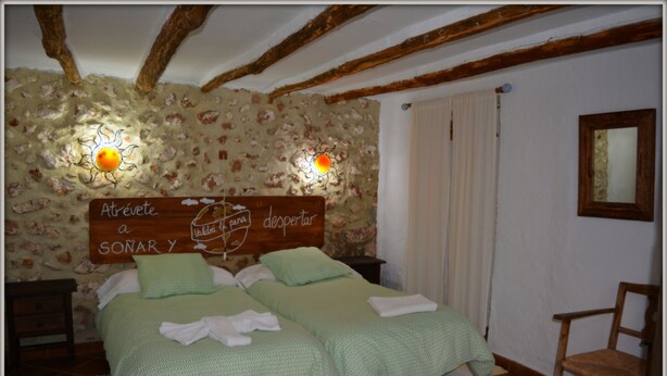 Une chambre à coucher avec un lit, une tête de lit en bois et deux lampes fixées au mur.