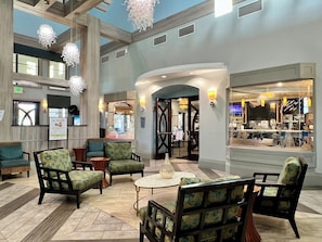 A spacious lobby with modern furniture, a reception desk, and a view of the restaurant area.