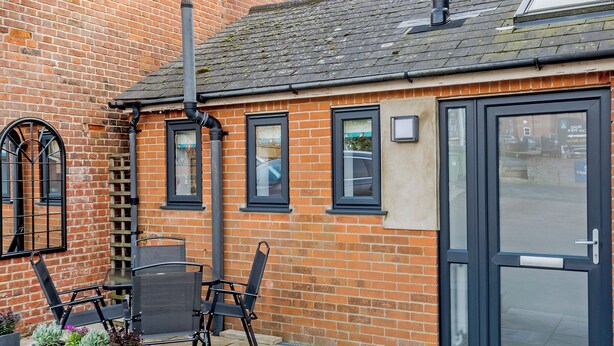 A brick building with a black door, windows, and a chimney. - 2 bedroom accommodation in Mundesley, near North Walsham (Mundesley, near North Walsham)