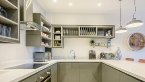A modern kitchen with built-in appliances, a central island, and a round shelf with decorative items. - 2 bedroom accommodation in Mundesley, near North Walsham (Mundesley, near North Walsham)
