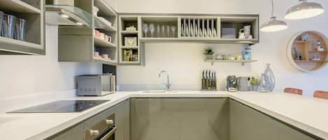 A modern kitchen with built-in appliances, a central island, and a round shelf with decorative items.
