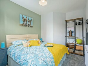 A bedroom with a bed, a nightstand, a dresser, and a shelf with decorative items. - 2 bedroom accommodation in Mundesley, near North Walsham (Mundesley, near North Walsham)
