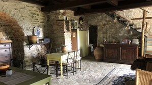 A rustic interior with stone walls, a wooden table with chairs, a large rug, and a staircase leading to another level. - Cascina Bertolotto Wine Resort. (Spigno Monferrato)