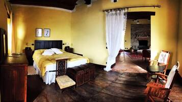 Una habitación tradicional con cama, muebles de madera, chimenea y zona de comedor.