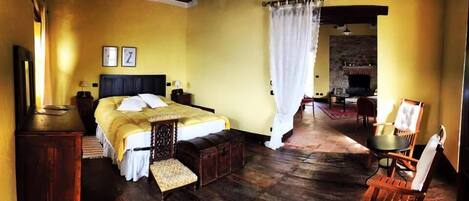 A traditional room with a bed, wooden furniture, a fireplace, and a dining area.